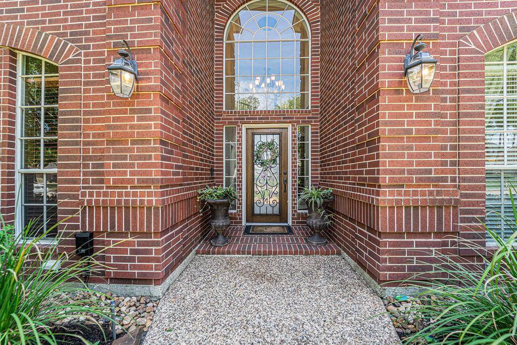 Step into elegance with this stunning brick entryway, showcasing soaring windows, a beautiful wrought iron front door, and impeccable curb appeal.