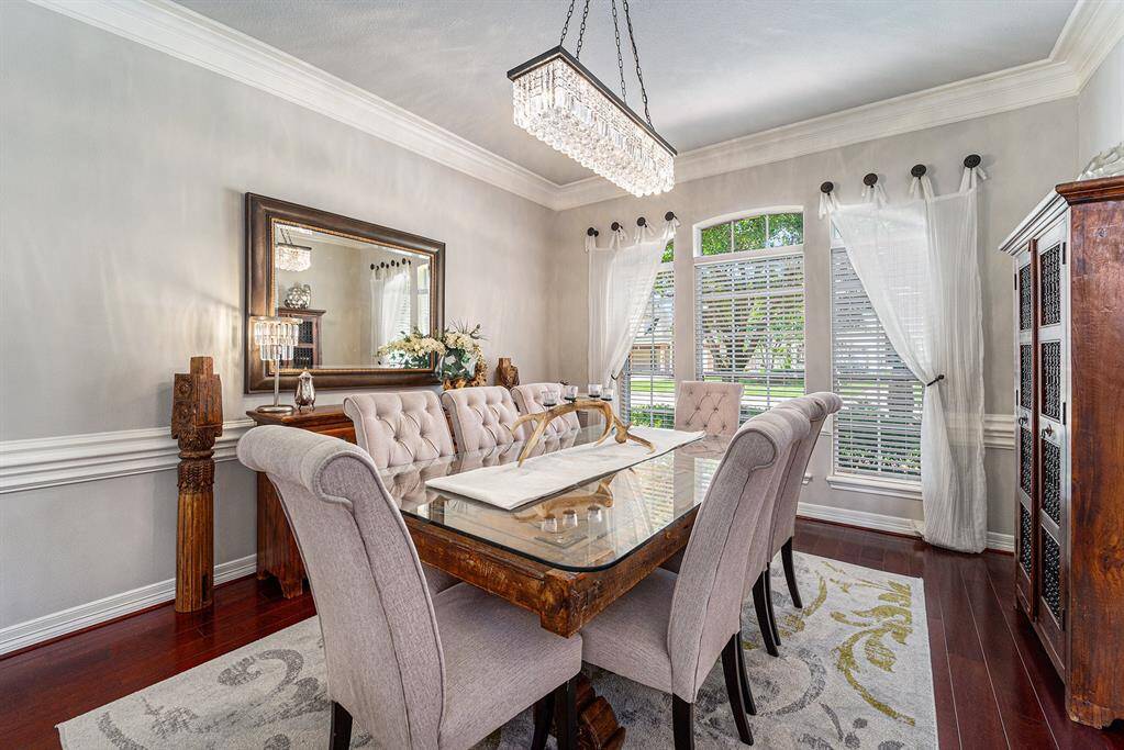 Elegant formal dining room with gorgeous chandelier with views of the front yard.
