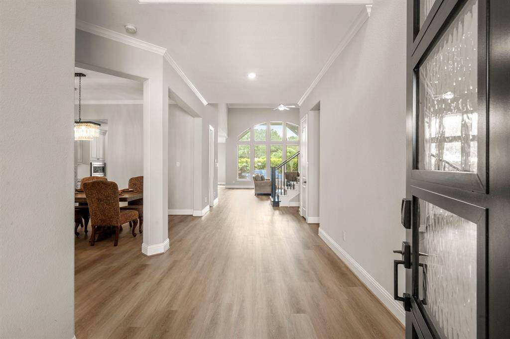 Step through a grand wooden front door with glass panels into an inviting entryway, where a stunning chandelier sets the tone for the elegance that continues throughout the home.