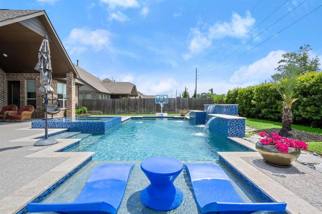 A gorgeous pool with a beach-entry, tanning shelf, waterfall features, and a large spa create a private resort vibe.