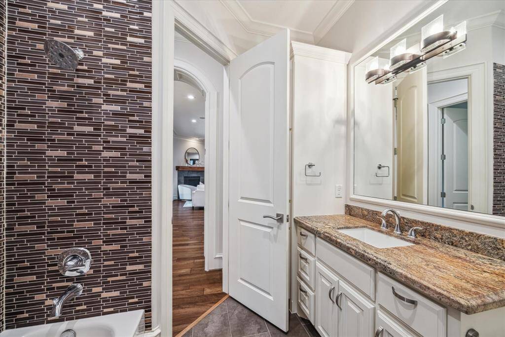 The secondary bathroom features sleek granite countertops and beautiful tile accents in the shower, offering a stylish and functional space.