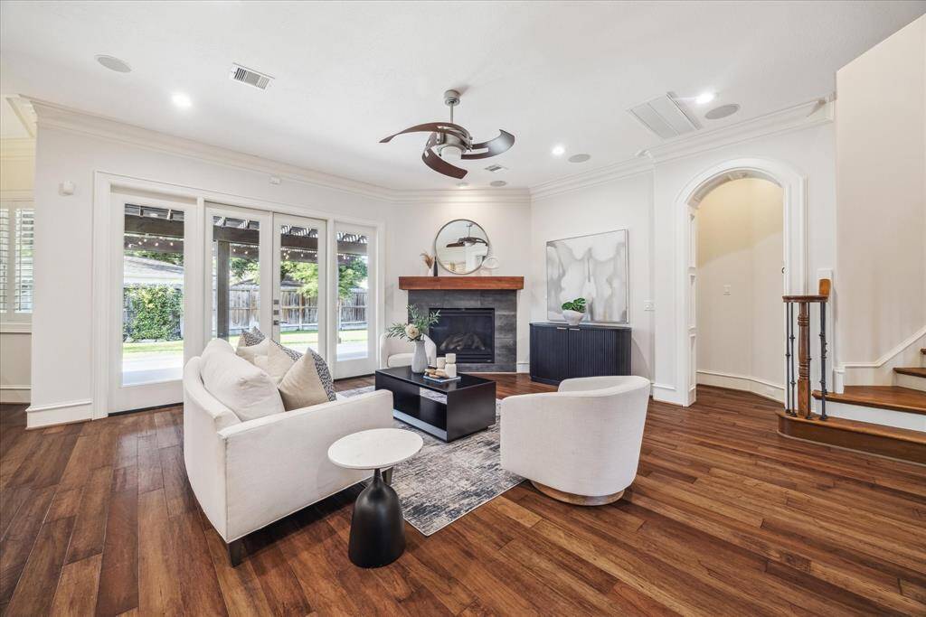 The family room features a stunning wall of windows that flood the space with natural light, offering beautiful views of the backyard. Double doors lead to the exterior, while built-in speakers enhance the atmosphere.