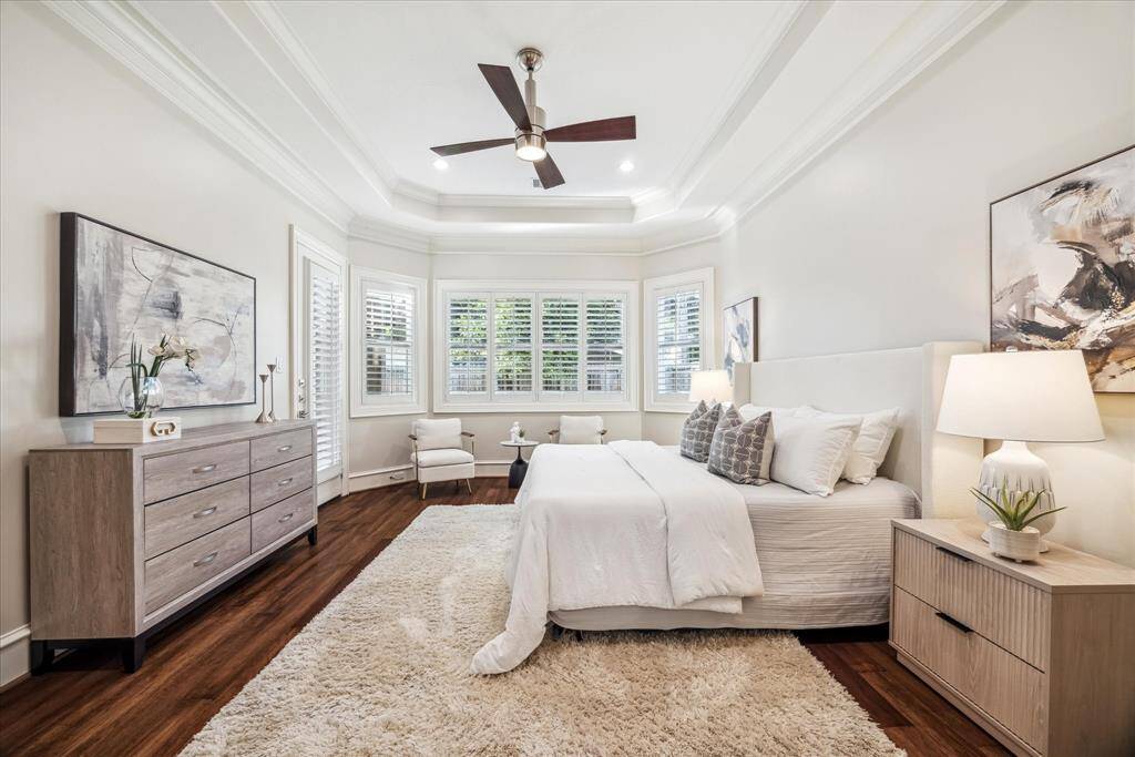 The primary bedroom offers a stunning tray ceiling and rich wood floors, creating a warm and inviting atmosphere.