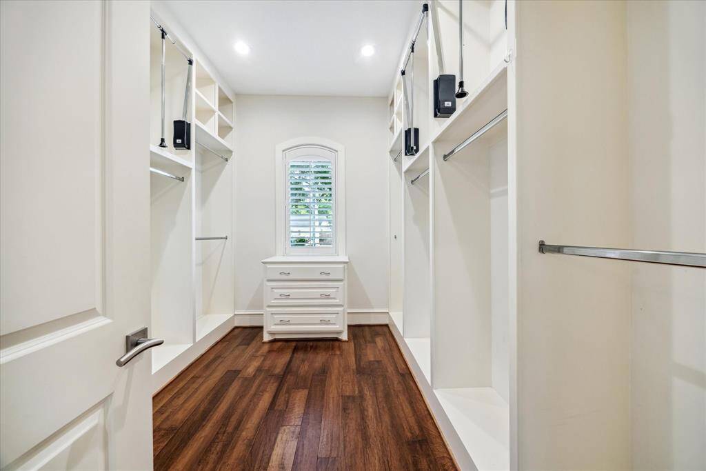 The expansive walk-in closet is a true standout, featuring pull-down rods for easy access to high shelves, built-in drawers for organized storage, and ample hanging space both up and down.