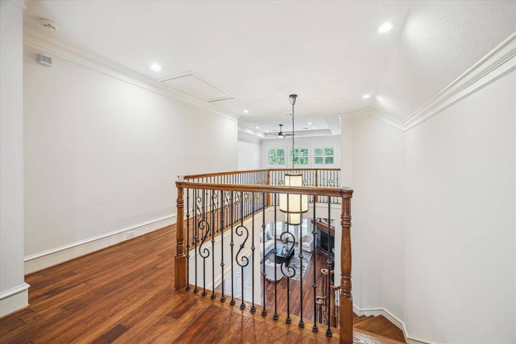 The upstairs landing offers a spacious and welcoming area, perfect for relaxing or displaying art. Overlooking the open floor plan below, it also features a nearby custom-built desk, providing an ideal home office nook.