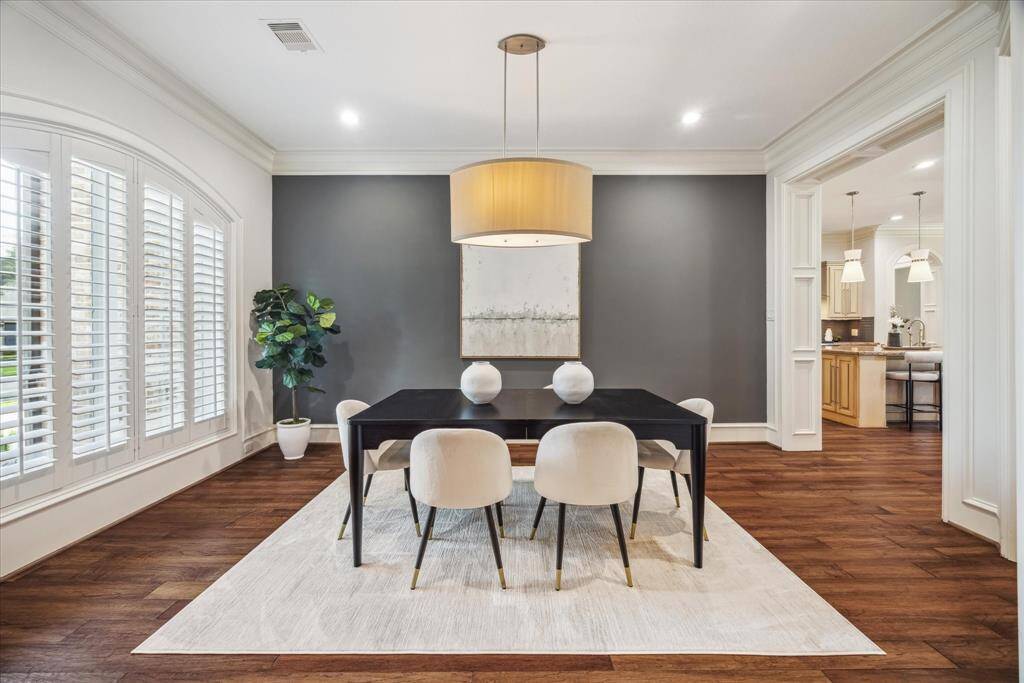 The formal dining room is a sophisticated space featuring an elegant accent wall, classic plantation shutters, and views of the front yard. Custom millwork and rich wood flooring create a warm, refined atmosphere—perfect for gatherings and celebrations.