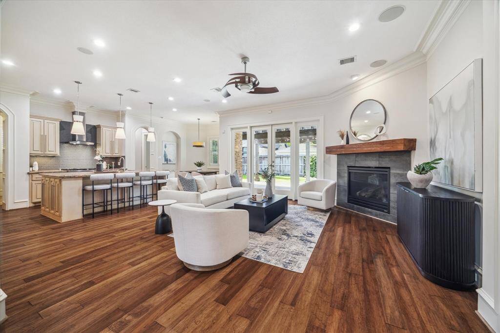The spacious family room is the heart of the home, featuring a large gas log fireplace with custom millwork, rich hardwood floors, and double doors that open to the back patio. This light-filled space blends comfort and style.
