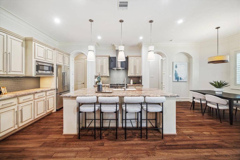 A chef’s dream kitchen—featuring a Viking 36” gas range, Viking refrigerator, custom soft-close cabinetry, and a spacious island with Crema Bordeaux countertops, storage, and seating.