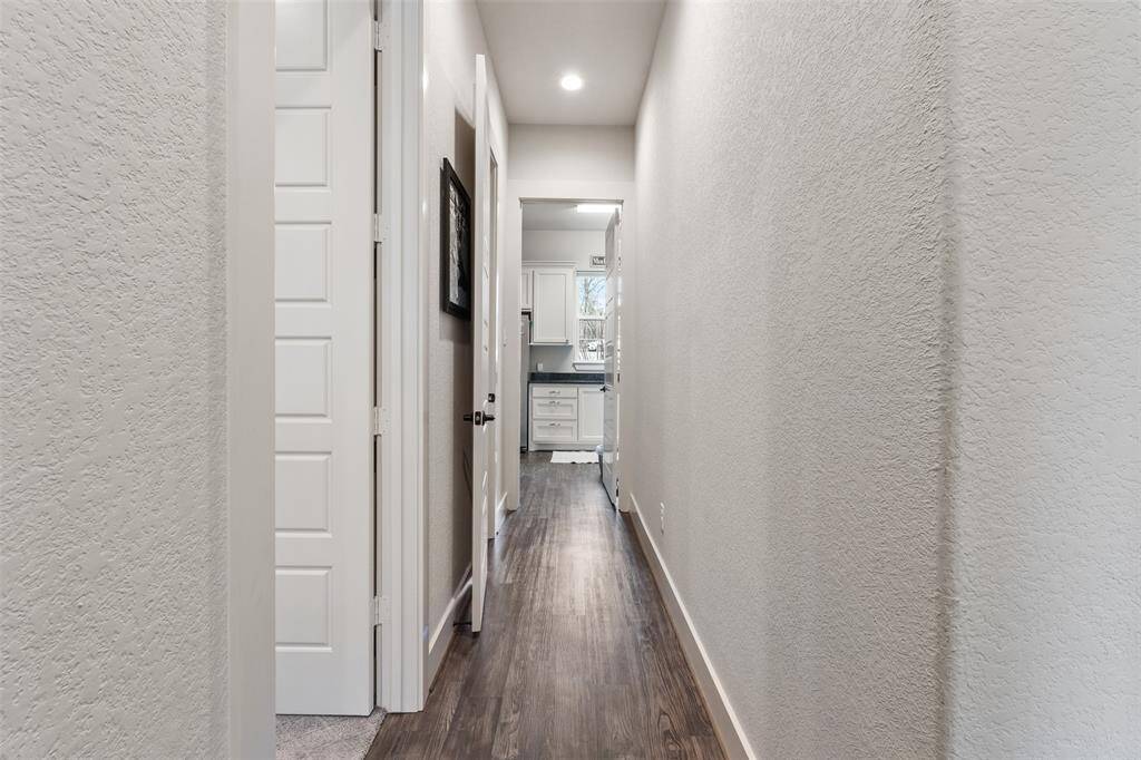 This hall way runs behind the kitchen and leads way to the primary bedroom, half bath and laundry room.