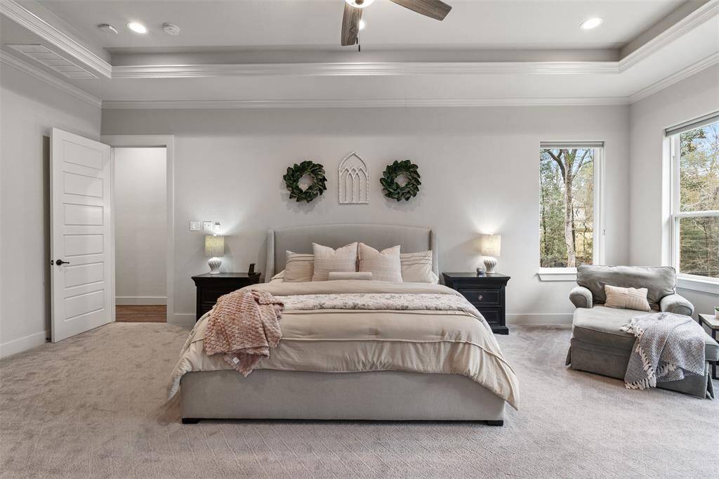 This large primary bedroom is complete with a sitting area and tray ceiling with additional lighting.