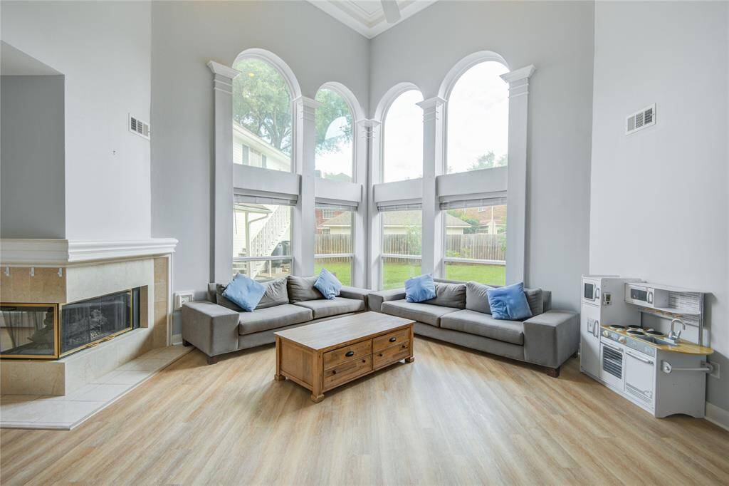 Now into the living space. This is such a comfortable space to relax, visit and just be with family. Sun-drenched living space with dramatic two-story ceilings. Sleek wood-like flooring, cozy fireplace, tons of charm.