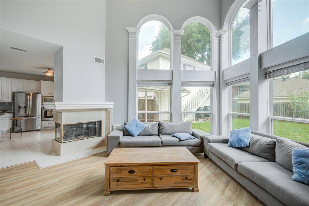Now into the living space. This is such a comfortable space to relax, visit and just be with family. Sun-drenched living space with dramatic two-story ceilings. Sleek wood-like flooring, cozy fireplace, tons of charm.