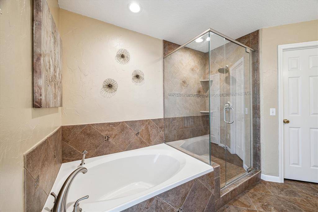 Large walk in shower with frameless glass doors, and soaking tub.