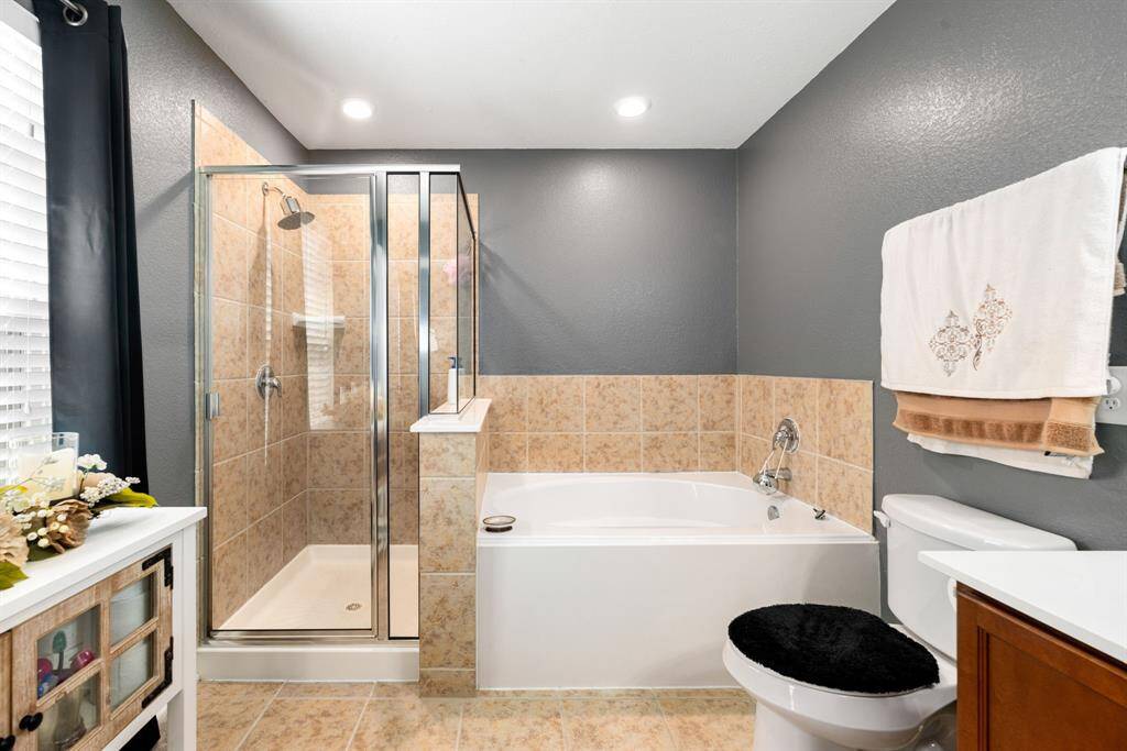 This additional view of the primary bath showcases a walk-in shower with tile surround and a separate garden tub perfect for soaking after a long day.