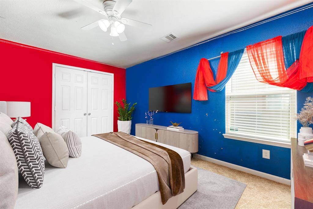 Secondary bedroom features plush carpet, custom paint, ceiling fan with lighting and a large window with privacy blinds.