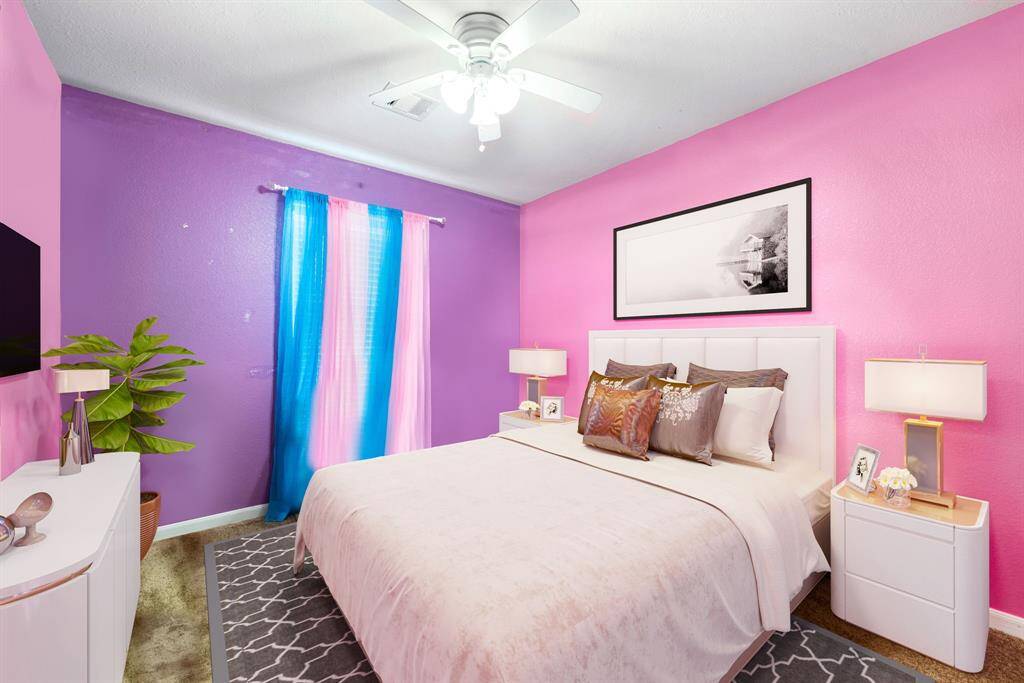 Secondary bedroom features plush carpet, custom paint, ceiling fan with lighting and a large window with privacy blinds.
