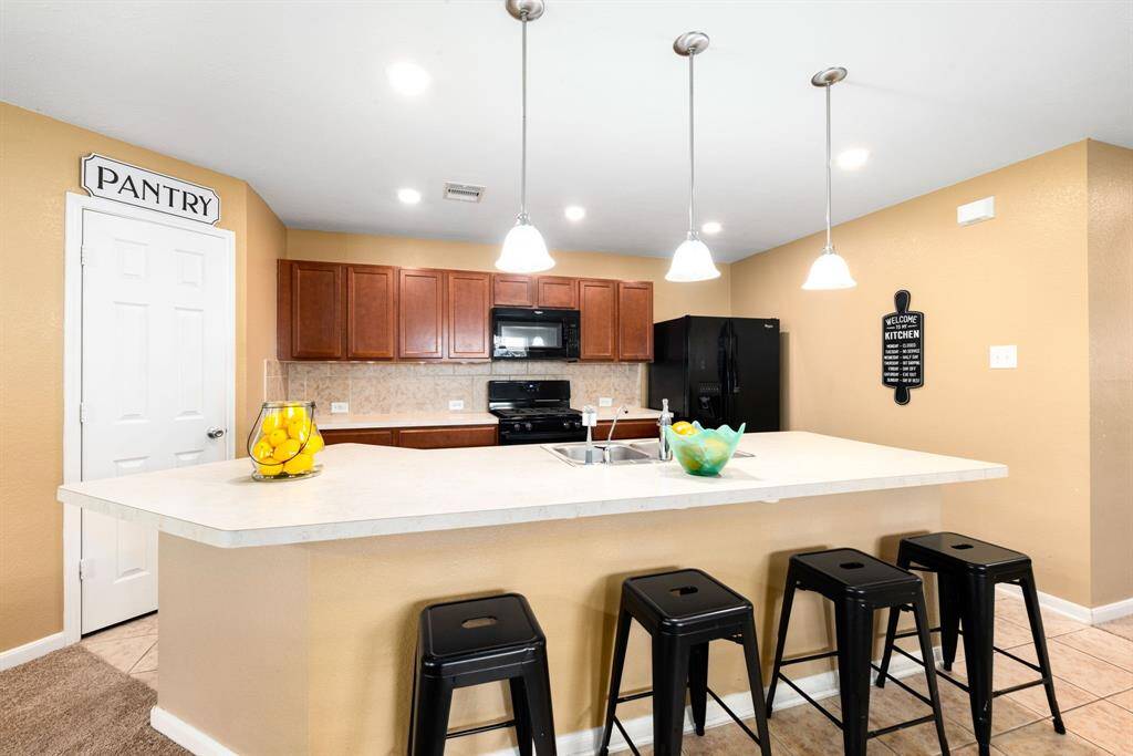 This kitchen is by far any chef’s dream! This spacious kitchen features high ceilings, dark stained wood cabinets, modern tile backsplash, recessed lighting with additional custom pendant lighting, extended counter space, kitchen island with double sink and space for breakfast bar and a walk-in pantry all overlooking your huge family room.