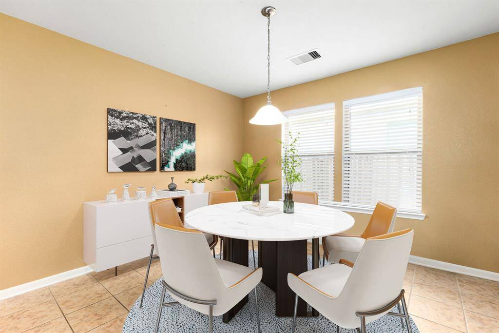 This lovely dining area is perfect for entertaining.  This space showcases custom paint, high ceilings, hanging pendant light, large window adding to the ample natural light in the kitchen, and tile flooring.