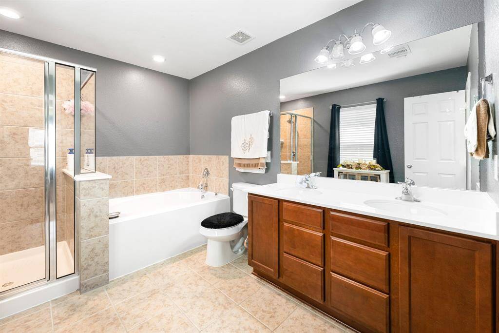 This primary bathroom is definitely move-in ready! Featuring a framed walk-in shower with tile surround, separate garden tub for soaking after a long day with custom tile detailing, dark stained cabinets with light countertops, spacious walk-in closet with shelving, high ceilings, custom paint, sleek and modern finishes.
