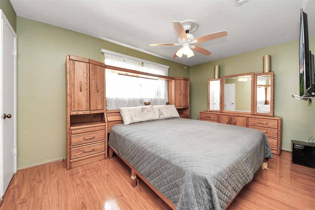 Spacious Primary bedroom beautiful flooring, a ceiling fan, and a large window providing natural light. The space is cozy and inviting.