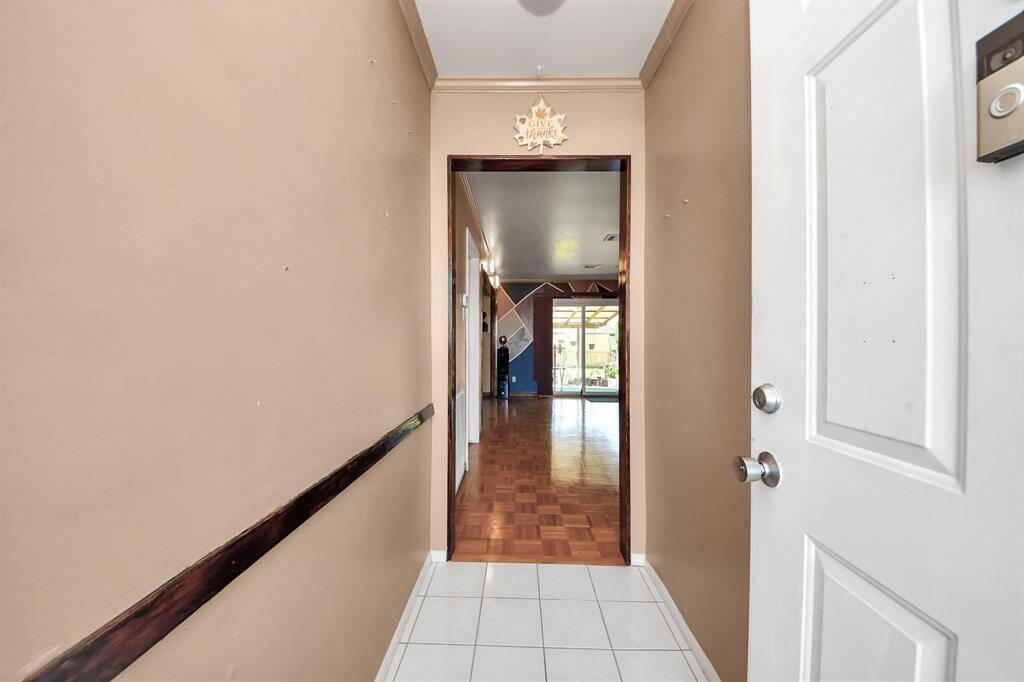 Bright and welcoming entryway features neutral walls and a patterned tile floor, leading into a wood floors room beyond.