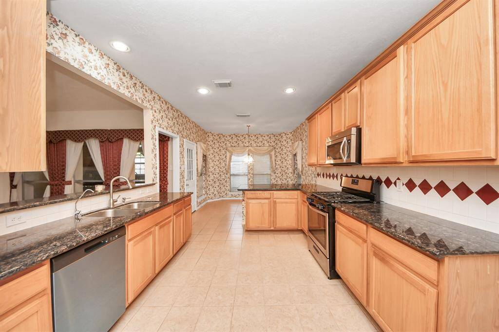 The kitchen features spacious granite countertops, abundant light wood cabinetry, and modern stainless steel appliances. It opens to a cozy dining area & breakfast nook.