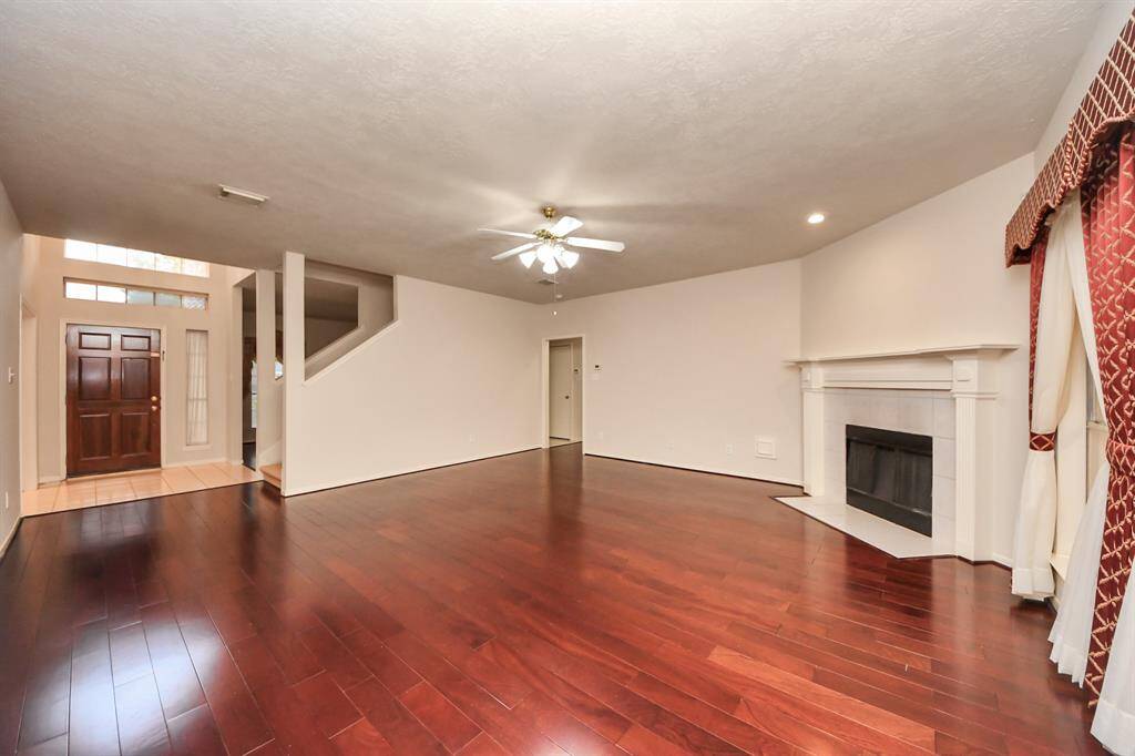 Spacious living room with rich hardwood floors and a cozy fireplace.