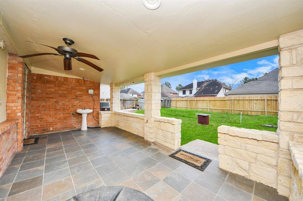Covered patio with a ceiling fan, gas connection, wash basin and tiled flooring.