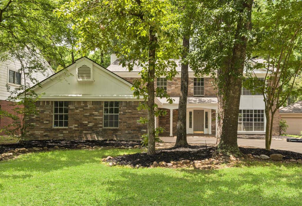 A picturesque front exterior adorned with lush trees and beautifully mulched landscaping areas, creating a serene and inviting curb appeal.