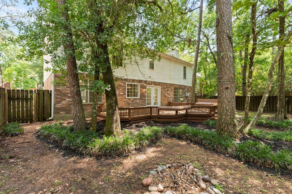 A charming backyard featuring a newly painted deck with built-in seating, perfect for entertaining. Surrounded by lush shaded trees, it includes a cozy firepit area ready for chairs, creating an ideal space for gatherings and relaxation.