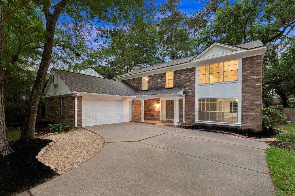 This stunning two-story brick home boasts large windows, a spacious two-car garage, and a charming front porch. Nestled among mature trees, it offers a peaceful and inviting wooded setting.