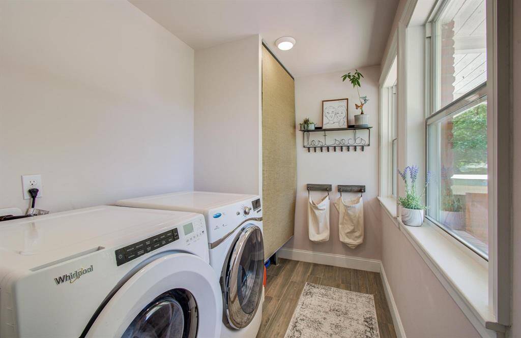 The functional utility room offers room for a large washer and dryer, with an abundance of storage space to keep everything organized. Natural light pours in through a large window, brightening the room and enhancing its efficient layout. The wood-like floor adds a touch of warmth and style.