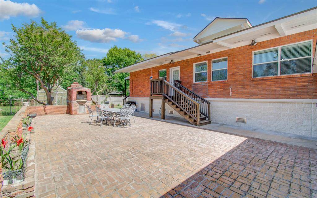 The spacious brick patio offers ample room for both relaxing in solitude or entertaining guests. Featuring a charming brick pizza oven and a welcoming dining area, it’s the perfect setting for al fresco meals. Surrounded by lush greenery, this serene outdoor space is seamlessly connected to the home, with a small staircase leading to a side entrance door, enhancing its flow and inviting atmosphere.