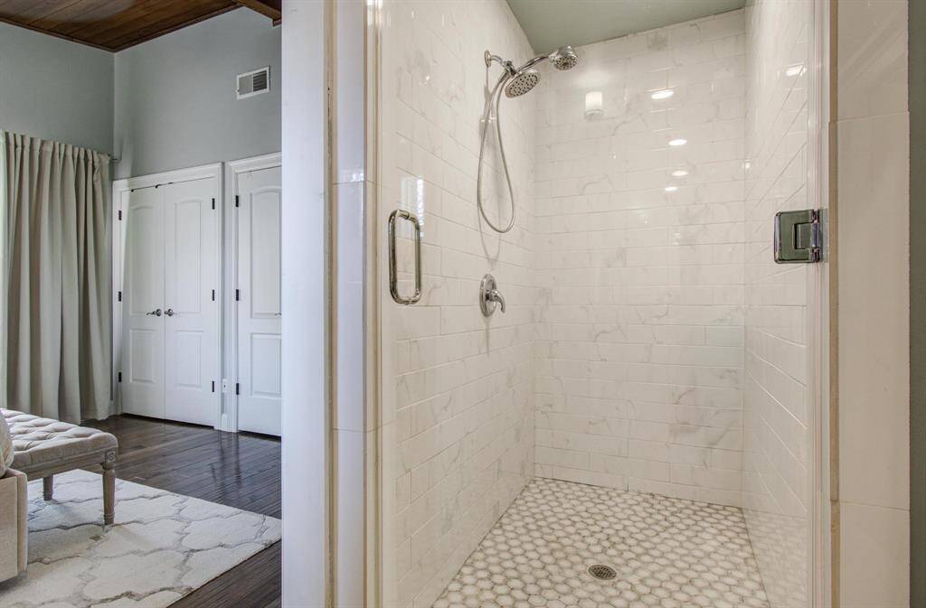 The updated primary shower is lined with sleek white tile, bringing a sense of freshness and simplicity to the room. The clean lines and thoughtful design complement the bathroom’s rustic character, creating a warm yet polished retreat.