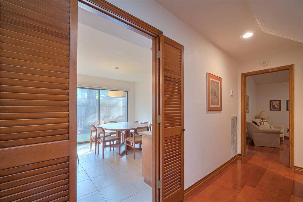 Located just off the formal dining room, this hallway leads to the primary bedroom and the breakfast area and kitchen, elegantly framed by stunning wooden louvered doors that add both style and character to the space.