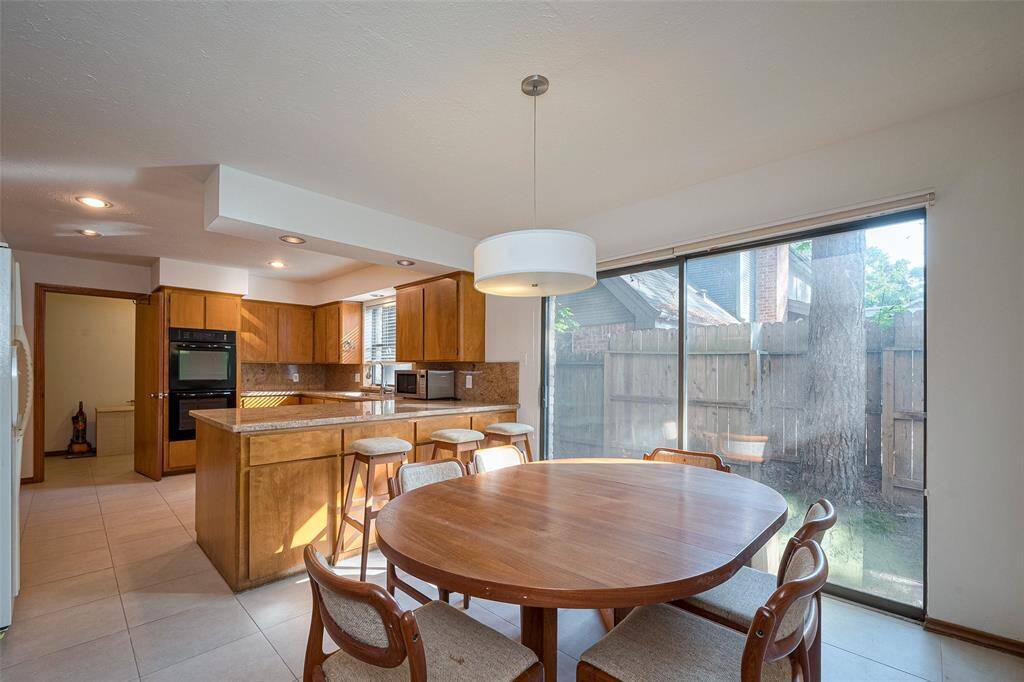 The breakfast area features a stylish designer pendant light fixture and sliding doors that open directly to the backyard, making it the ideal spot to enjoy peaceful mornings while taking in the beautiful views of the backyard and deck.