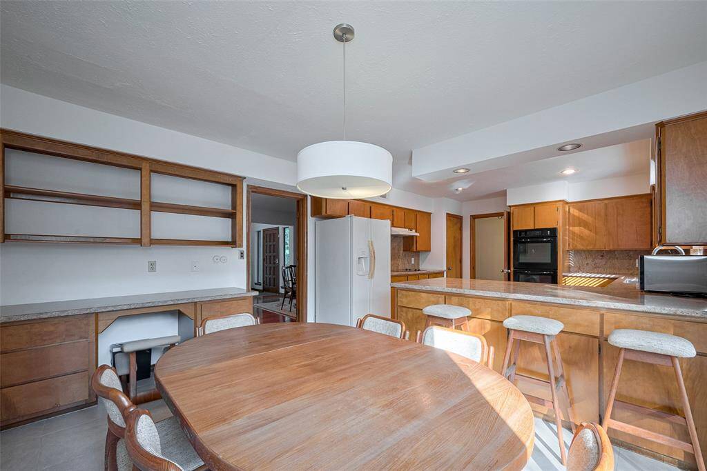 The breakfast area overlooks the gourmet kitchen and it features abundant natural light, recessed lighting, and ample shelving and cabinetry, providing plenty of storage space while maintaining a functional and organized layout.