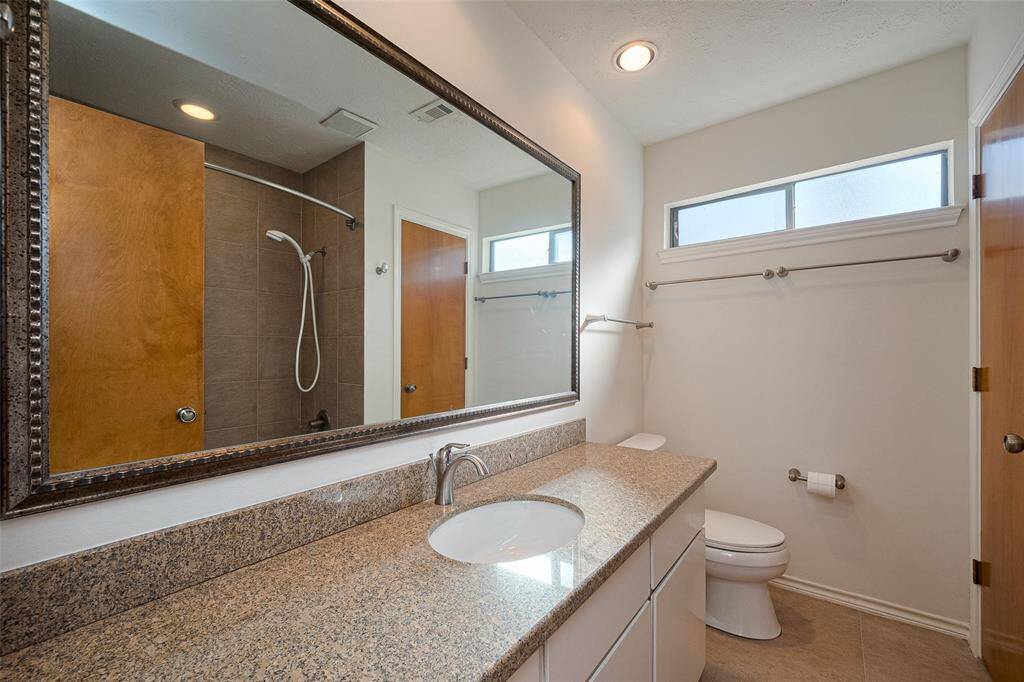 The shared upstairs bath features a spacious vanity with ample counter space and a large mirror, along with a convenient shower-tub combo, offering both functionality and comfort.