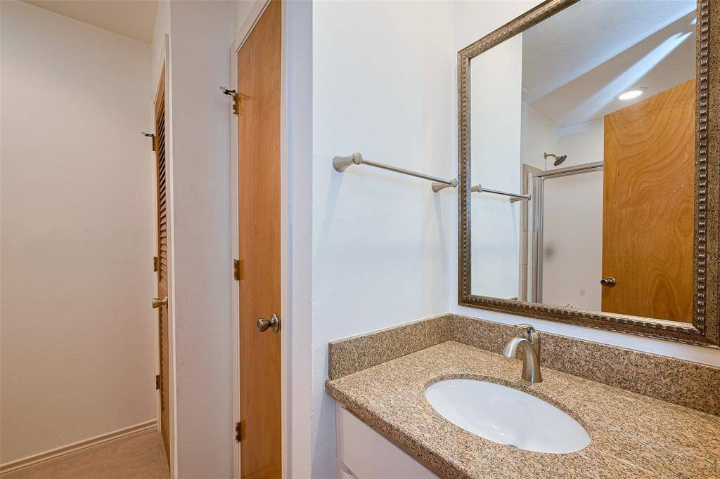 The en-suite bath features a well-appointed vanity with generous counter and storage space, complemented by a sleek standing shower for a functional and stylish retreat.