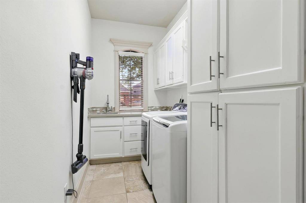 Located out of sight for the guests, laundry room features a gleaming stainless steel sink sits beneath a window offering a direct view of the adjacent house.