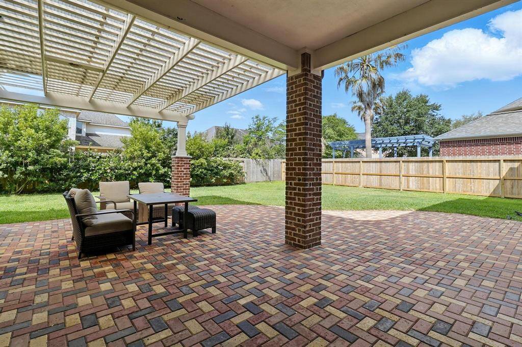 The traditional backyard covered patio offers a comfortable and elegant extension of the home. The patio itself is likely constructed from classic materials like brick, flagstone, or stained concrete, creating a timeless foundation. The cover, often supported by sturdy wooden or painted columns, provides ample shade, making it a pleasant space even on warm Houston afternoons.