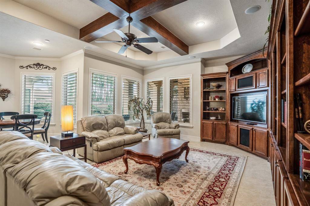 The living room offers elegant coffered ceilings with wooden beams and plenty of space for all of your friends and family. Natural light pours in through multiple windows with upgraded wood shutters.