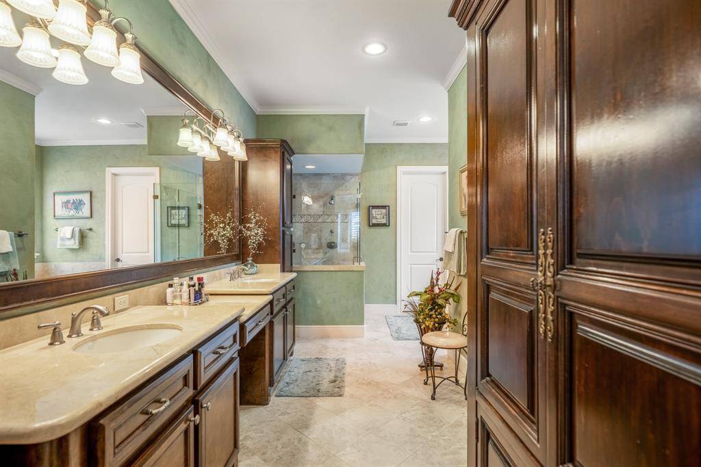 The primary bathroom exudes tranquility with its soft light green walls, creating a calming ambiance. A freestanding soaking tub invites relaxation, complemented by a spacious glass-enclosed walk-in shower. Dual sinks with an expansive vanity offer ample space, while two large closets with built-in shelving ensure organized storage. A separate water closet provides added privacy.