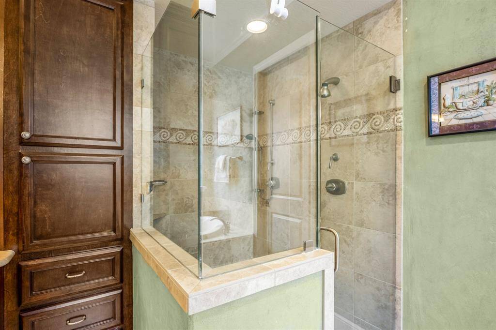 Adjacent to the soaking tub is a spacious walk-in glass shower, featuring a frameless design that adds a touch of elegance.