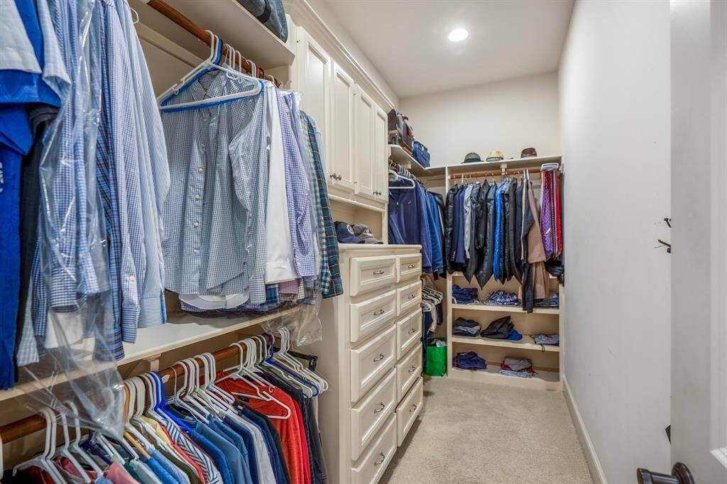 View of the second primary closet with tall built-ins plus a bolted safe. No sharing necessary!