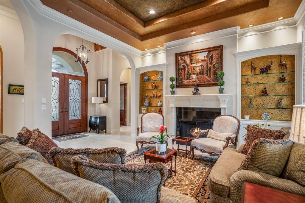 As you enter through the handsome double doors, you will notice the intricate arched ceiling in the foyer. Beyond the entry is the formal sitting room featuring a gas fireplace flanked by custom bookshelves and a custom painted recessed ceiling.