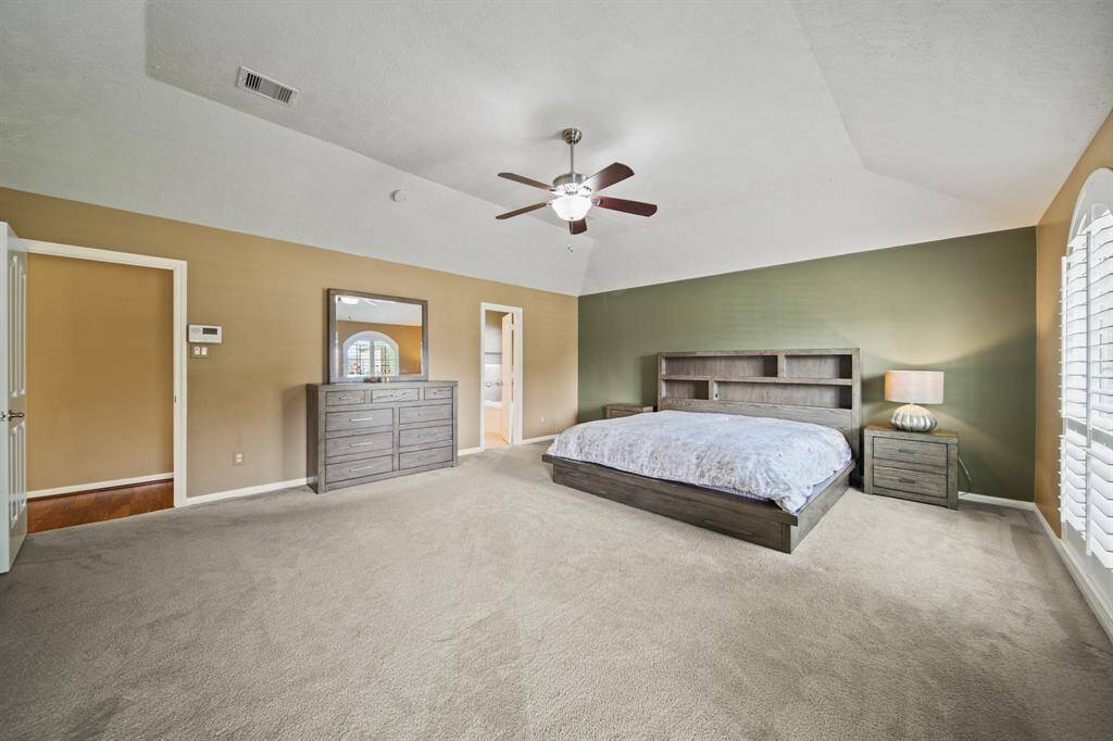 Spacious prime bedroom with arched windows, abundant natural light and a neutral color palette.