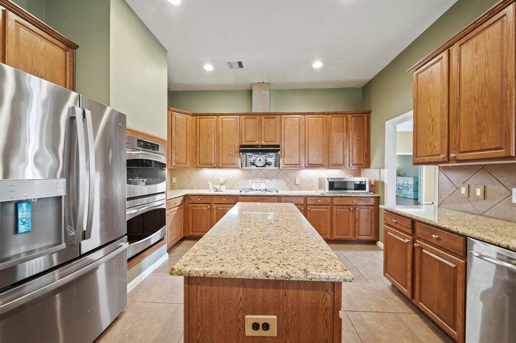 Chef's island kitchen with double ovens, abundant cabinets, and granite countertop