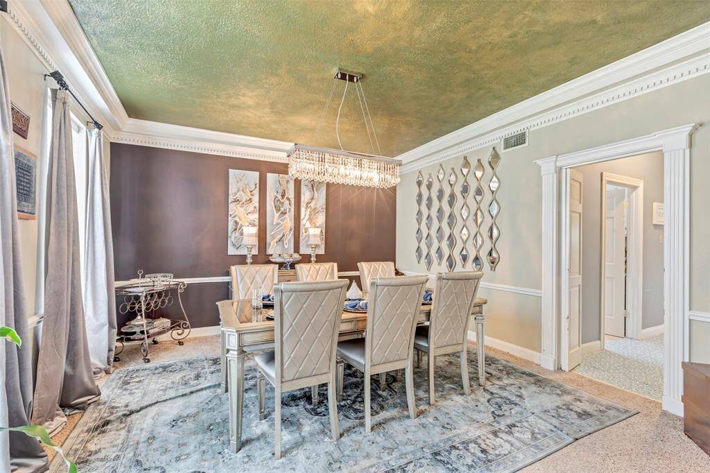 This elegant dining room features a luxurious chandelier. The room is bright and airy, with large windows creating a cozy and warm atmosphere.