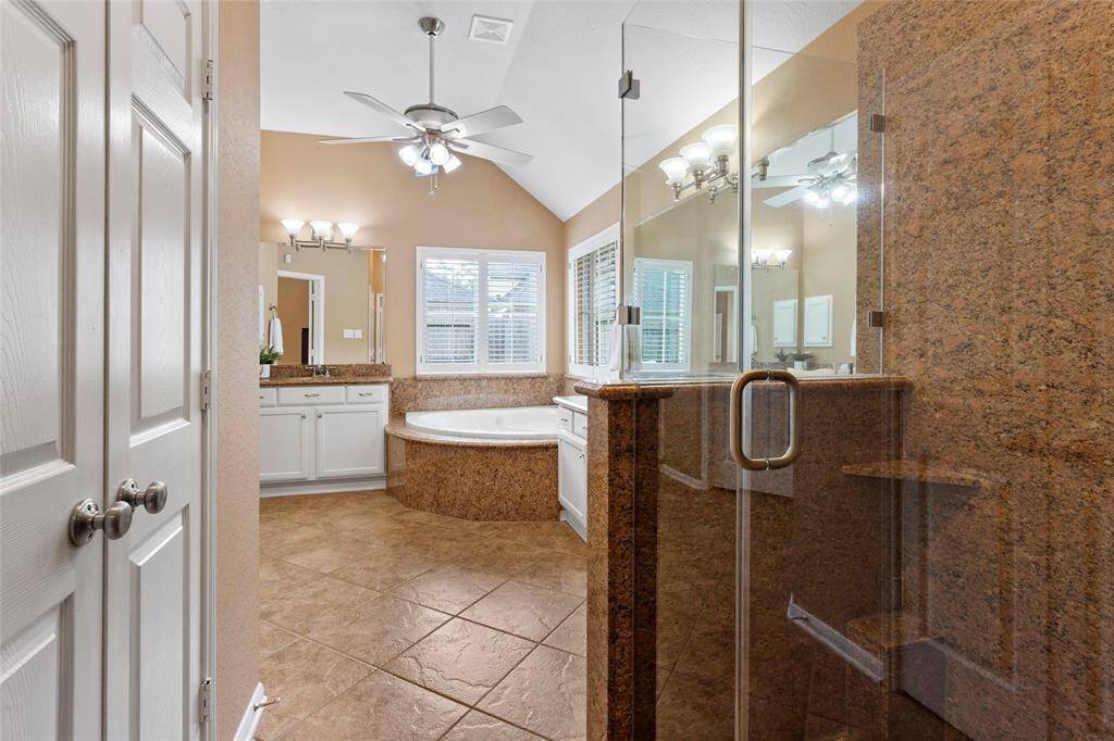 A large jetted, soaking tub, glass-enclosed shower, and double vanity compliment this large Primary Bathroom.